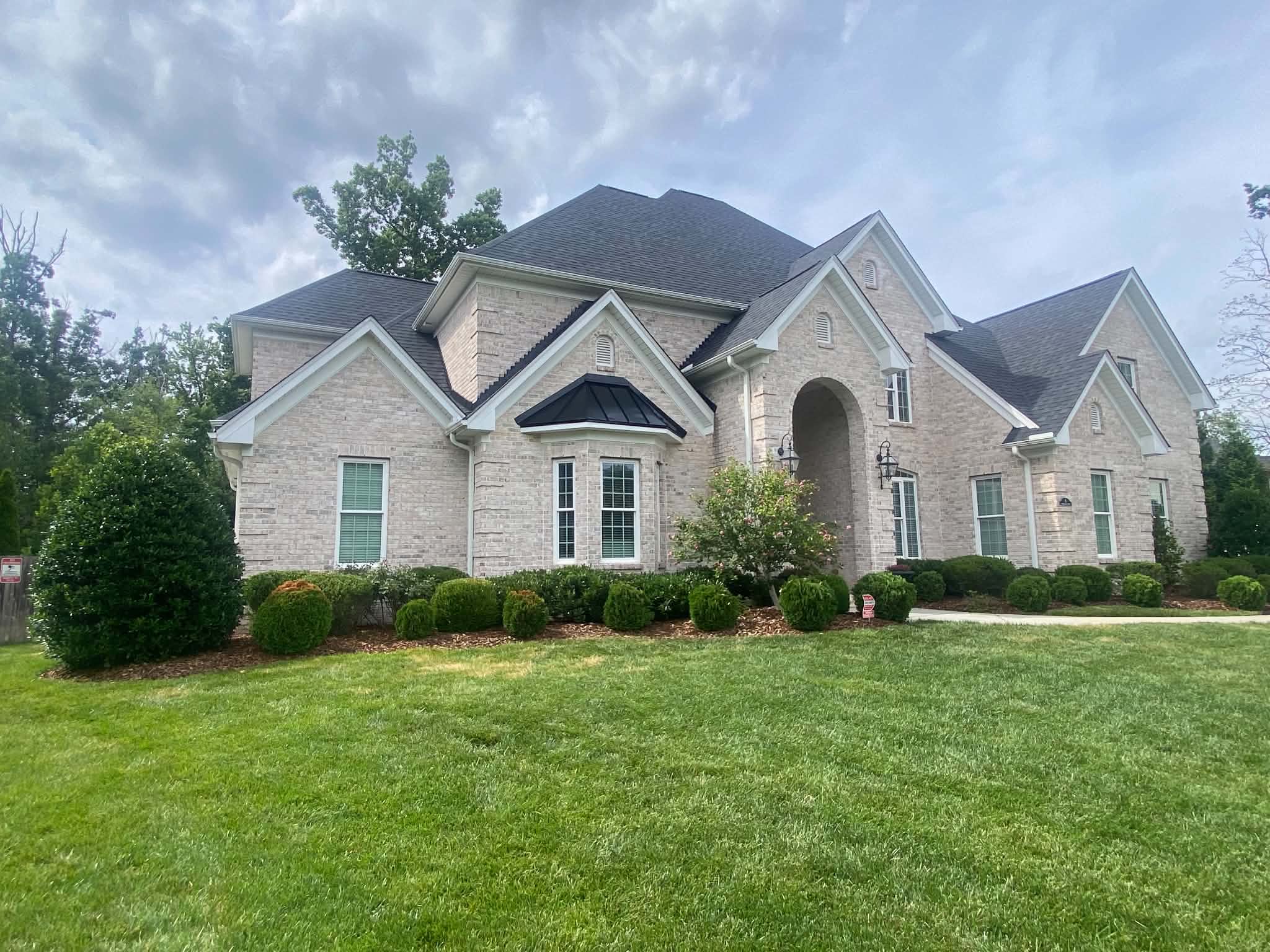 Completed dark shingle roof on a large brick home